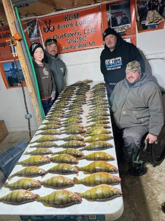 Volunteers and participants stand behind a table covered with rows of crappies.